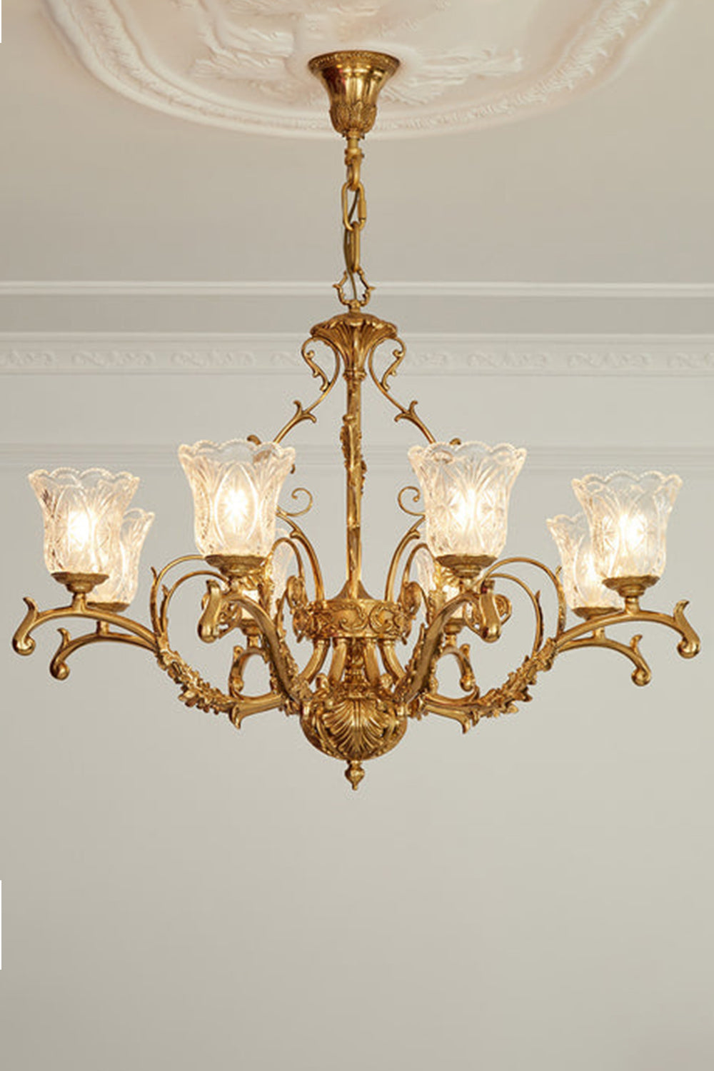 Beatrix Acanthus Leaf Chandelier | Ornate Brass and Frosted Carved Glass | Symmetrical view of the fully illuminated gold chandelier hanging from an ornate ceiling medallion | vexa lamps