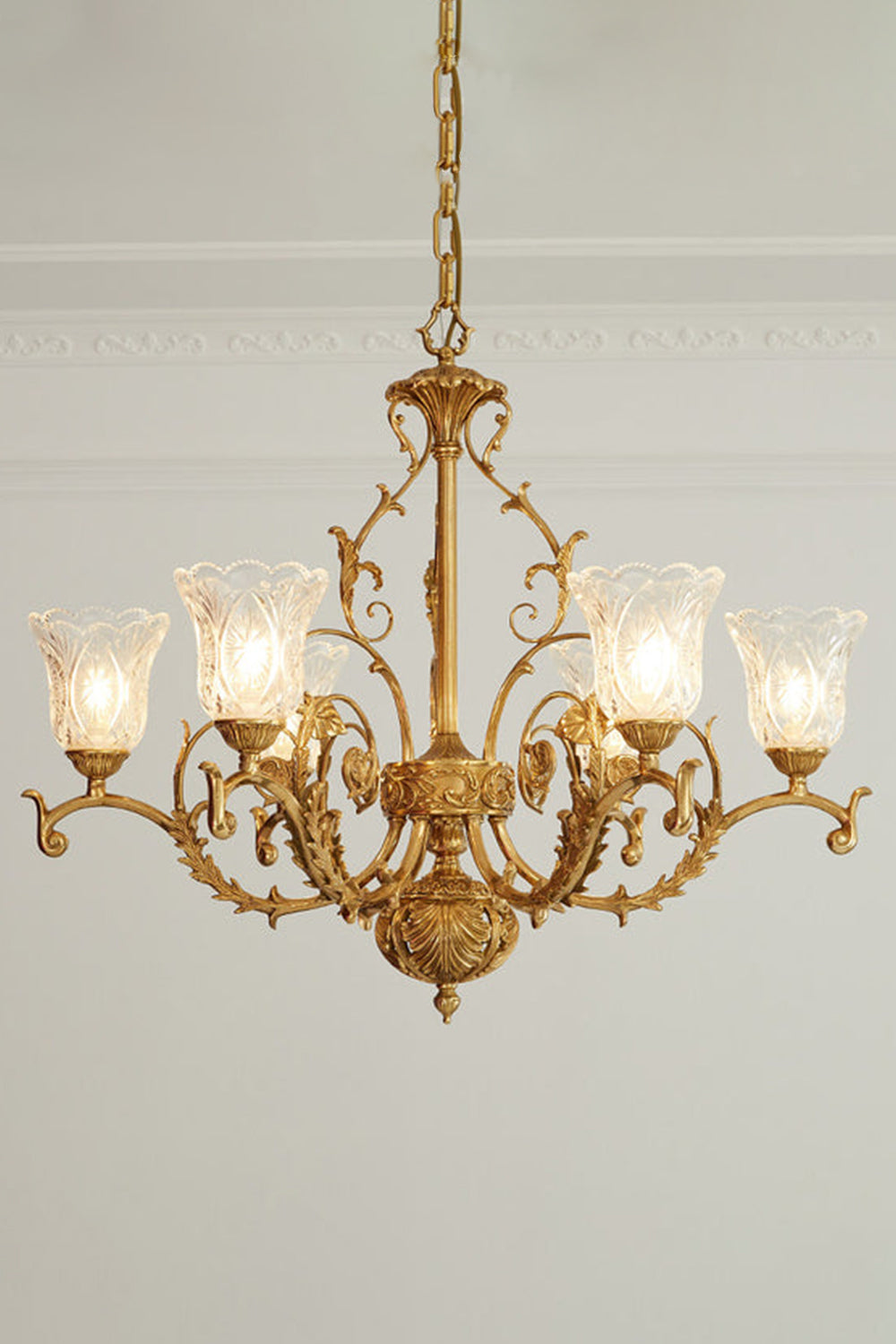 Beatrix Acanthus Leaf Chandelier | Ornate Brass and Frosted Carved Glass | Full studio presentation of the classic French-style brass fixture glowing warmly against a light wall | vexa lamps