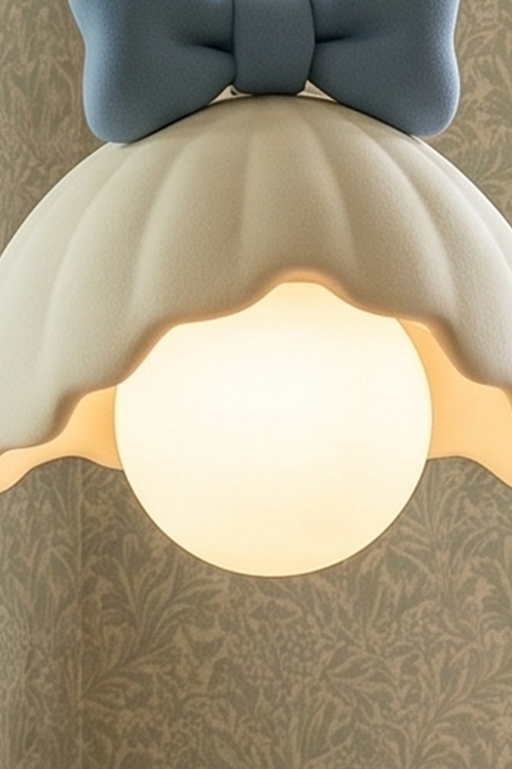 Bella Bow Arched Floor Lamp | Metal, Resin | Upward angled close-up view showing the warm spherical bulb illuminated under the blue bow scalloped shade structure | Detail shot | vexa lamps