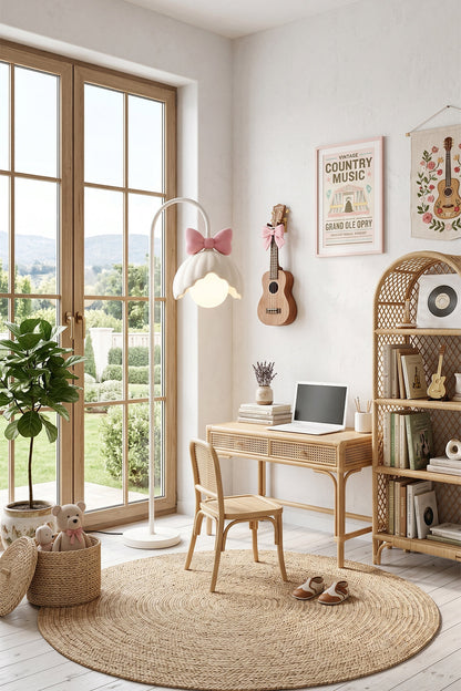 Bella Bow Arched Floor Lamp | Metal, Resin | Pink bow version standing on a round jute rug next to a light wood children's study desk and high arched window | vexa lamps