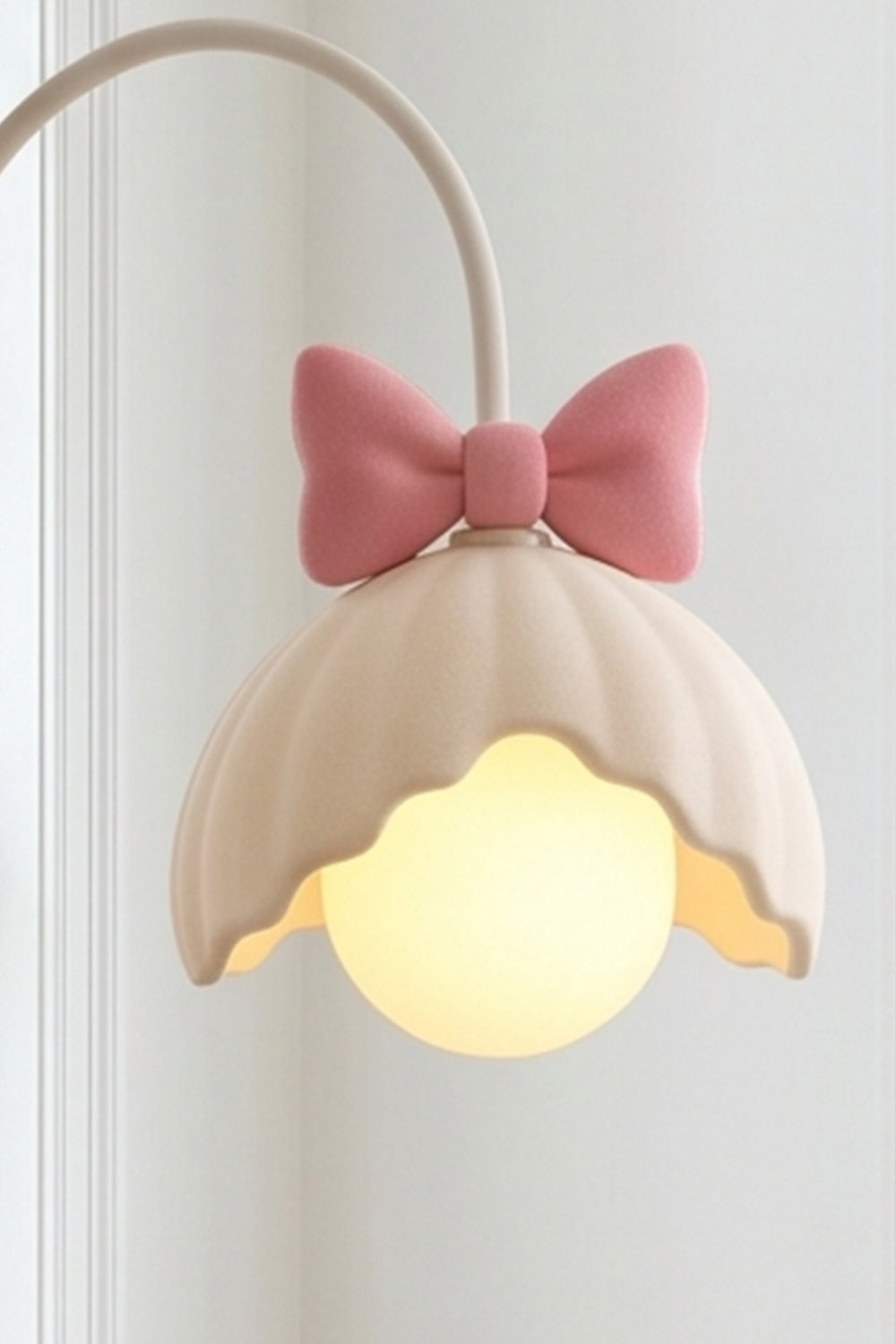 Bella Bow Arched Floor Lamp | Metal, Resin | Close-up side profile of the lit pink bow variant showcasing the glowing round glass globe bulb under the scalloped shade | Detail shot | vexa lamps