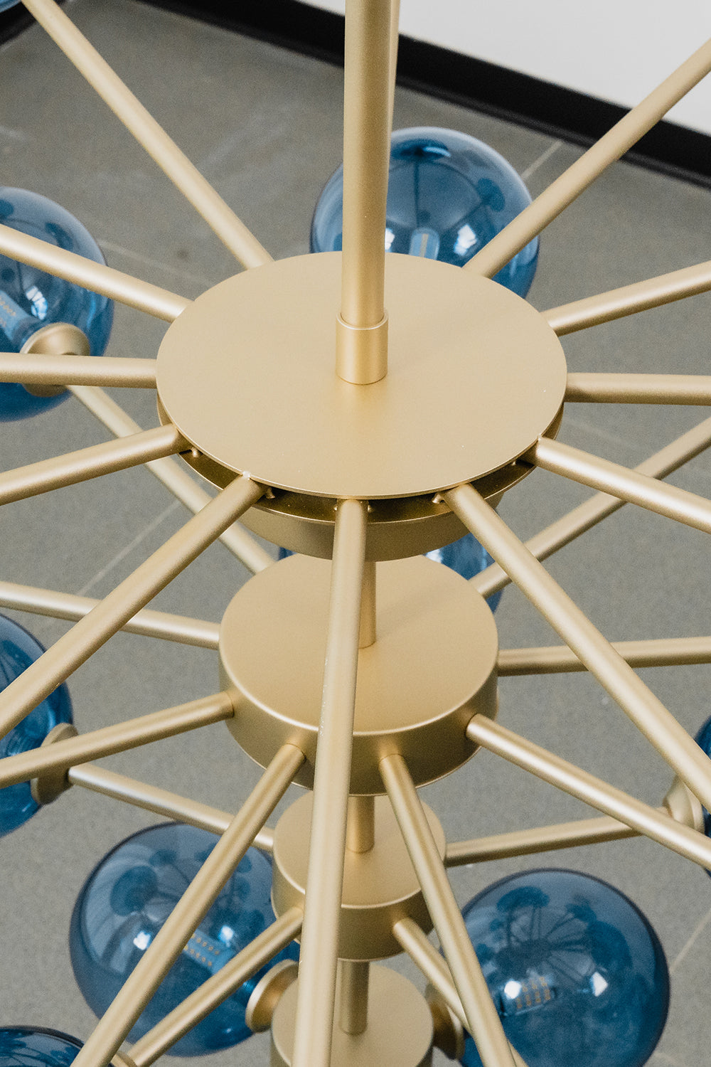 Blue Glass Bubble Globe Tiered Chandelier | Blue Glass and Brass Metal | Macro shot highlighting the central gold-finished metal hub and structural connection details | vexa lamps