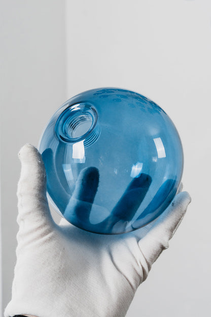 Blue Glass Bubble Globe Tiered Chandelier | Blue Glass and Brass Metal | A person wearing a white glove holding a single translucent blue glass globe sphere | vexa lamps