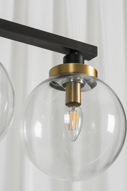 Brooks Linear Glass Globe Chandelier | Glass, Metal | Close-up unlit structural view focusing on a single transparent glass globe shade, gold collar accent, and internal filament bulb | Detail shot | vexa lamps