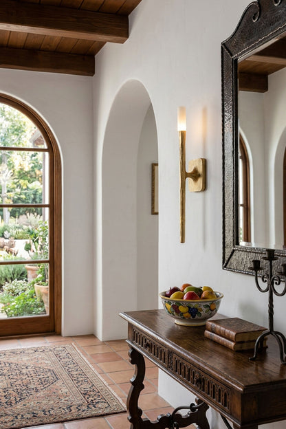 Bryony Torch Alabaster Brass Wall Lamp illuminating a hallway with a wooden console table and decor.