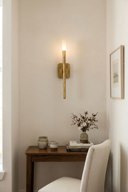 Bryony Torch Alabaster Brass Wall Lamp illuminating a cozy corner with a wooden table and chair.