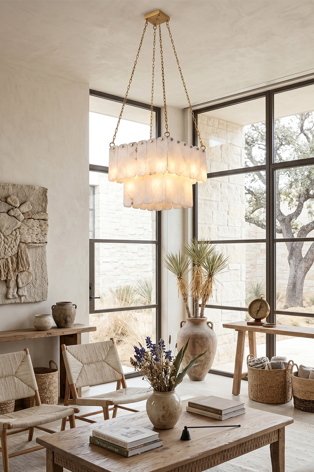 Callista Tiered Alabaster Chandelier | Alabaster, Metal | Positioned elegantly over a coffee table in a sunlit modern lounge space featuring woven pottery, plants, and lightweight lounge chairs | vexa lamps