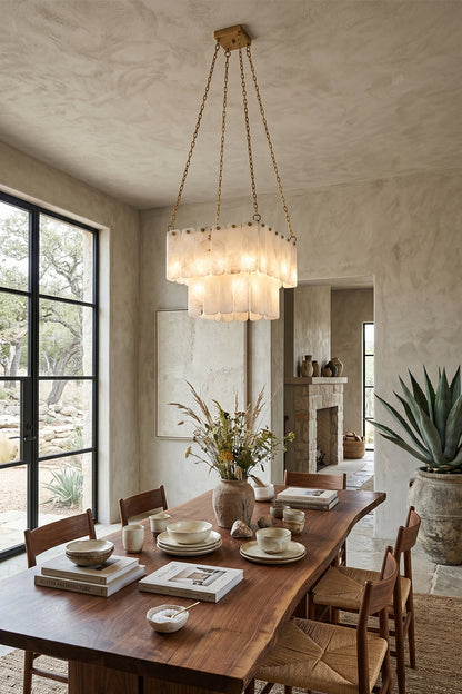Callista Tiered Alabaster Chandelier | Alabaster, Metal | Suspended over a modern wooden dining table set with white tableware in a sophisticated dining room next to a large potted plant | vexa lamps