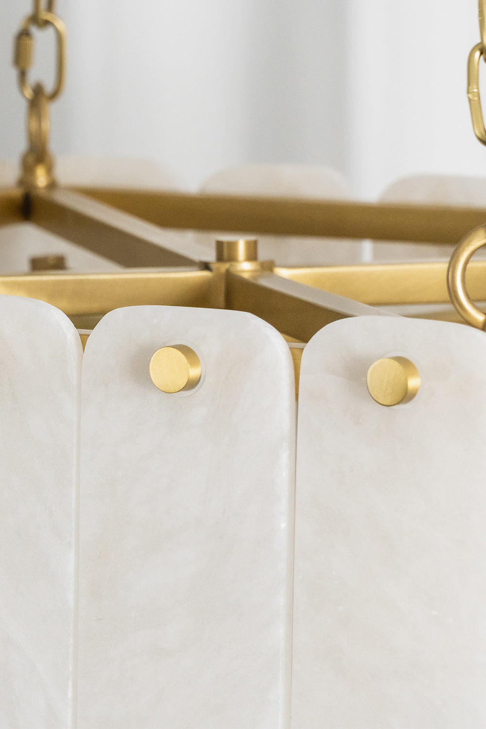 Callista Tiered Alabaster Chandelier | Alabaster, Metal | Close-up shot showing white alabaster stone slats fixed cleanly to the internal gold metal frame via round polished brass button rivets | Detail shot | vexa lamps