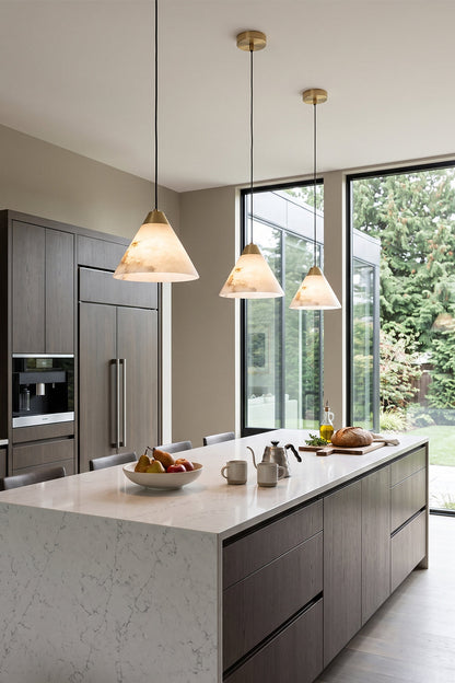 Caspian Conical Alabaster Pendant Light | Natural Alabaster and Brass | A row of three pendants illuminating a modern kitchen island with a clean marble counter | vexa lamps