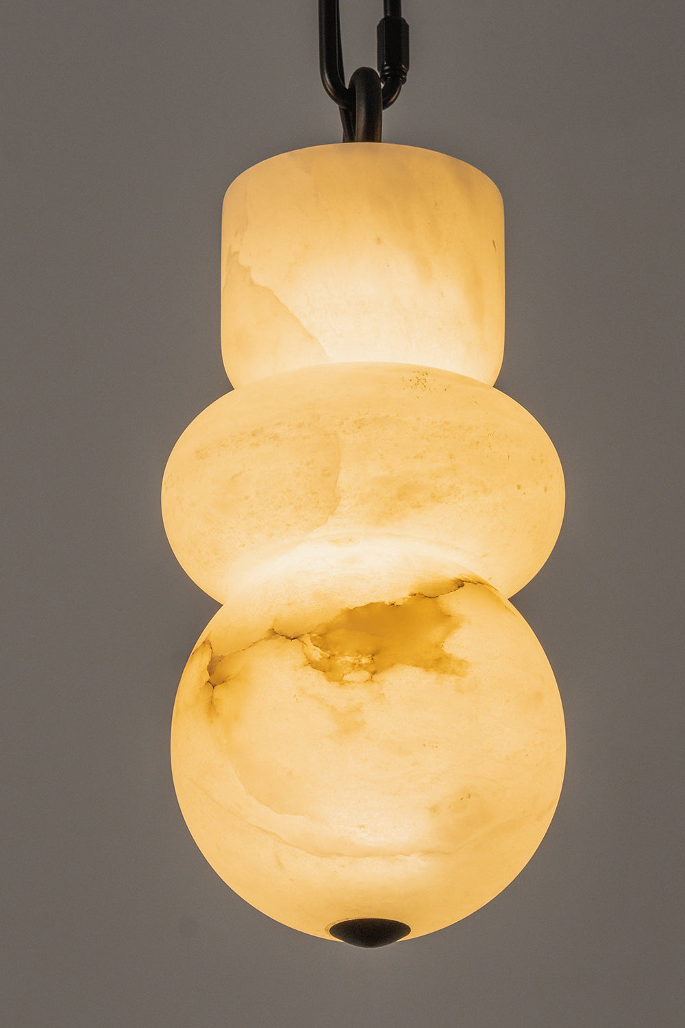 Alabaster pendant detail | Alabaster, Metal | Close-up of lit organic stone shade with black chain | vexa lamps