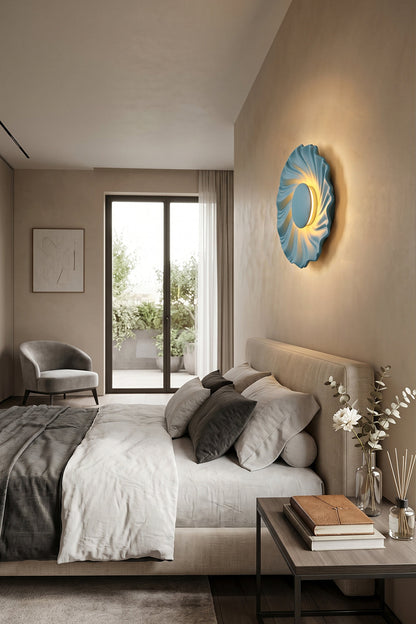 Centripetal Solstice Metal Wall Lamp | Metal, Resin | Blue textured lamp positioned as a bedside accent light in a minimalist modern bedroom with grey bedding and natural wood flooring | vexa lamps