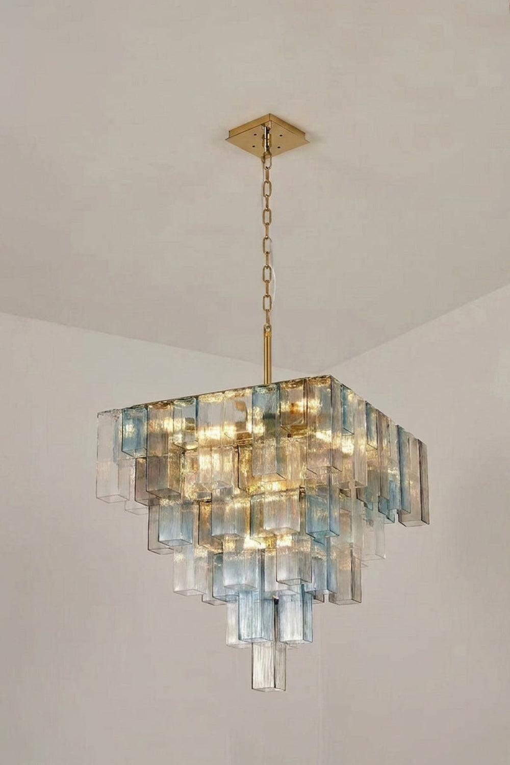 Clarissa Tiered Square Glass Chandelier | Studio Lit View | Studio presentation of the fully illuminated tiered square glass chandelier hanging against a clean off-white background wall | vexa lamps
