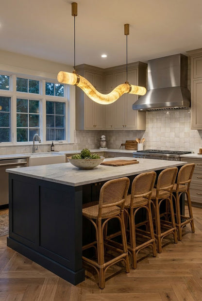 Undulating alabaster pendant lighting | Alabaster, Brass | Over a navy blue kitchen island with wooden stools | vexa lamps