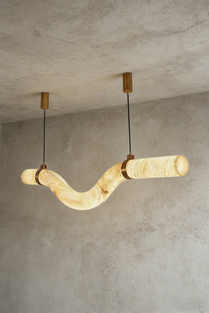 Lit undulating alabaster tube chandelier against grey ceiling | Alabaster, Brass | Side perspective showing the organic shape | vexa lamps