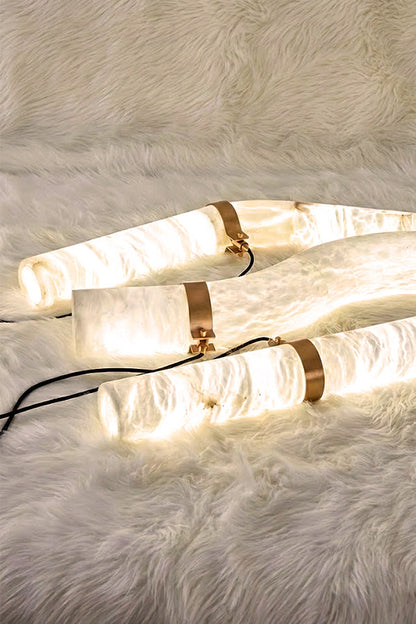 Close-up of three lit alabaster tubes on fur surface | Alabaster | Showing the natural stone grain and warm glow | vexa lamps