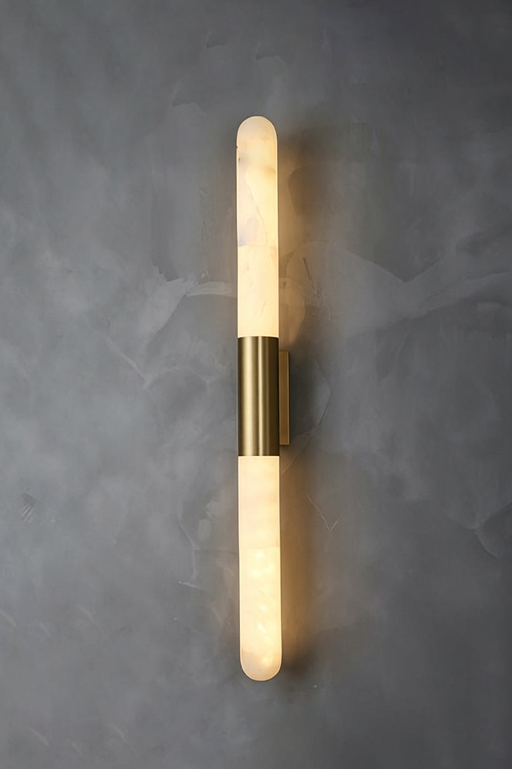 Corin Linear Alabaster Wall Sconce featuring a sleek design with alabaster and gold-toned frame on a gray wall.