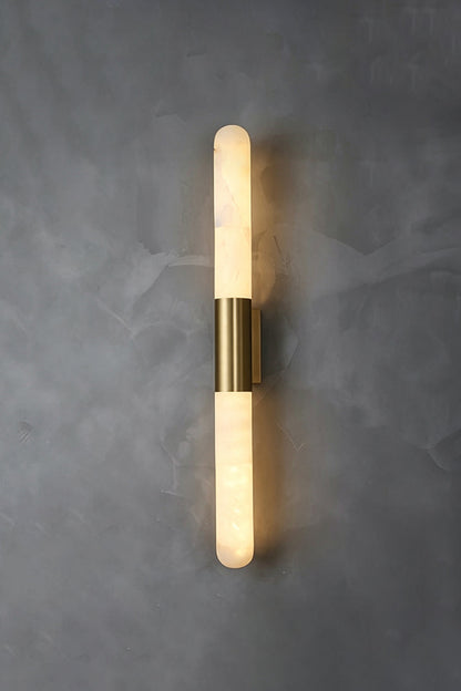 Corin Linear Alabaster Wall Sconce on a gray wall, featuring a warm glow from the alabaster and gold-toned frame.