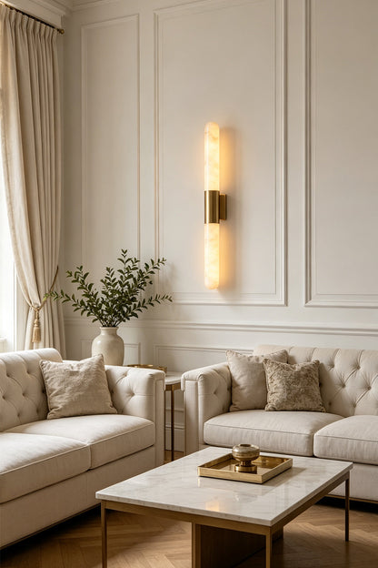 Corin Linear Alabaster Wall Sconce illuminating a stylish living room with elegant furnishings and warm tones.