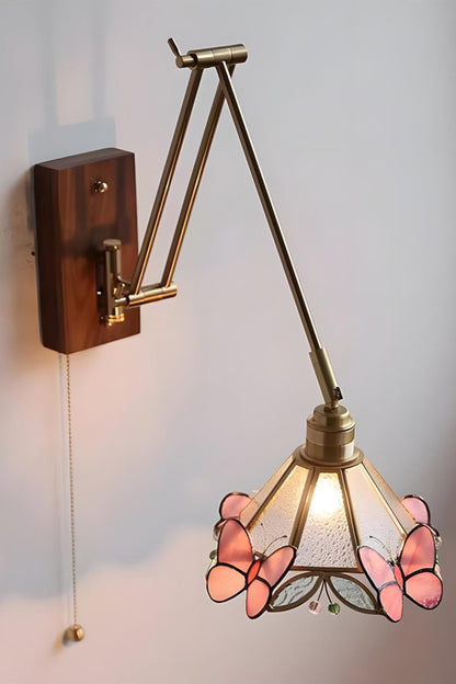 Cynthia Butterfly Articulated Wall Lamp | Stained Glass, Metal, Wood | Frontal angled view of the fully illuminated glass butterfly wall lamp casting a soft golden glow against a plain white wall | vexa lamps