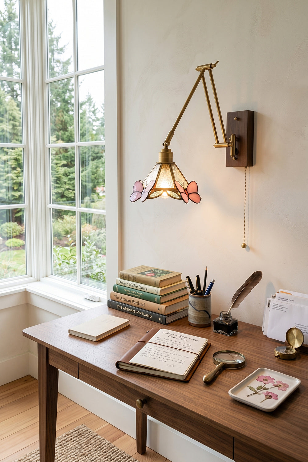 Cynthia Butterfly Articulated Wall Lamp | Stained Glass, Metal, Wood | Positioned as a functional desk task light over a traditional wooden writing table next to a large window with scenic views | vexa lamps