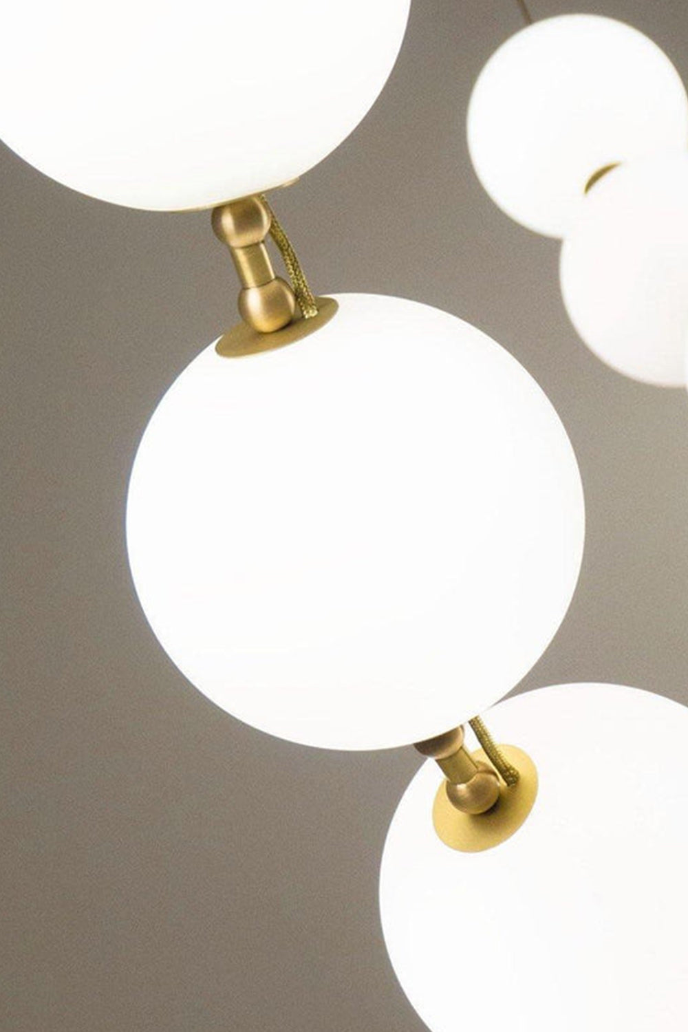 Close-up of the Delphine Pearl Strand Chandelier showcasing matte-white globes and brass accents.