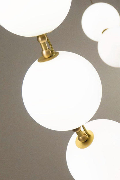 Close-up of the Delphine Pearl Strand Chandelier showcasing matte-white globes and brass accents.
