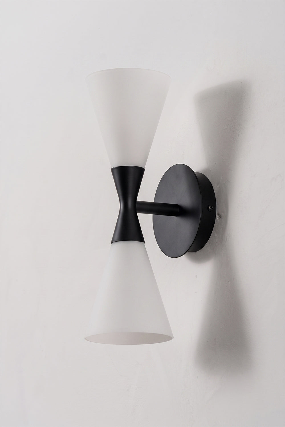 Diabolo Symmetry Glass Wall Sconce featuring dual conical glass shades mounted on a black wall plate.