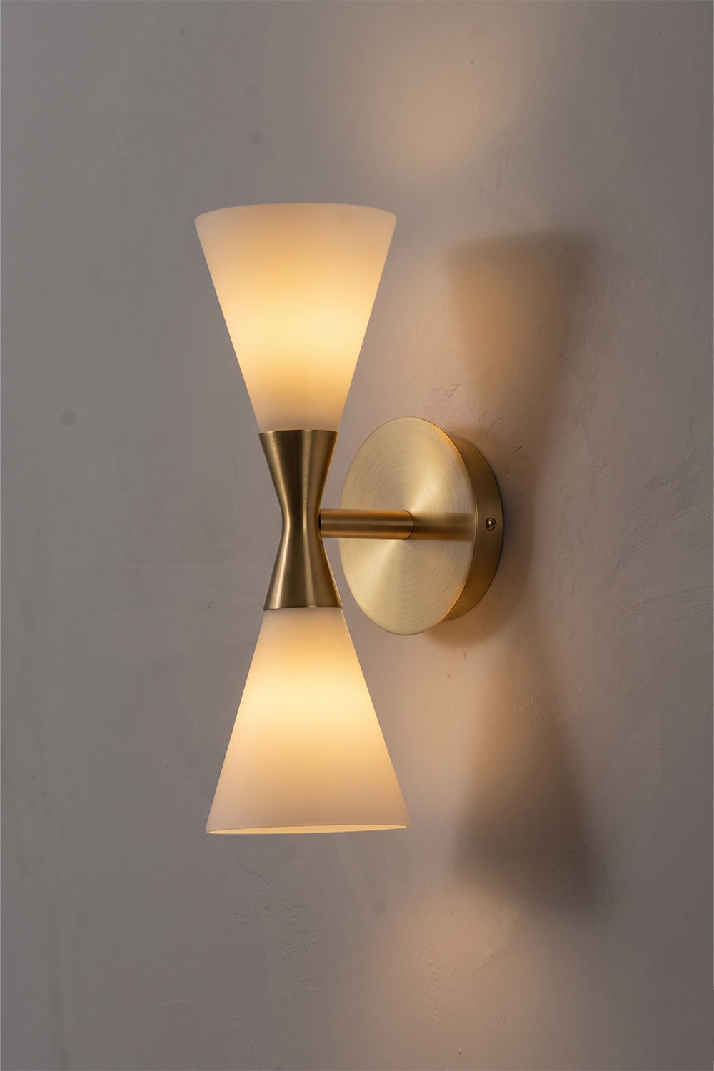 Diabolo Symmetry Glass Wall Sconce featuring dual conical opaque glass shades and a brushed brass axis.