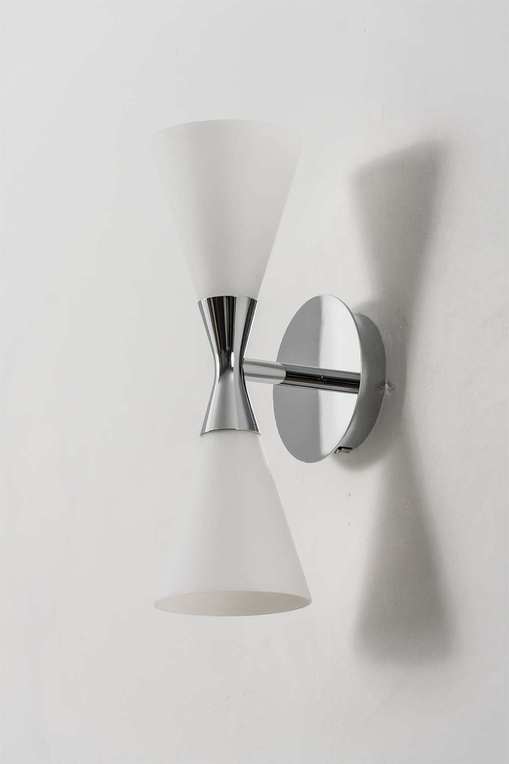 Diabolo Symmetry Glass Wall Sconce featuring dual conical glass shades and a sleek chrome finish on a modern wall.
