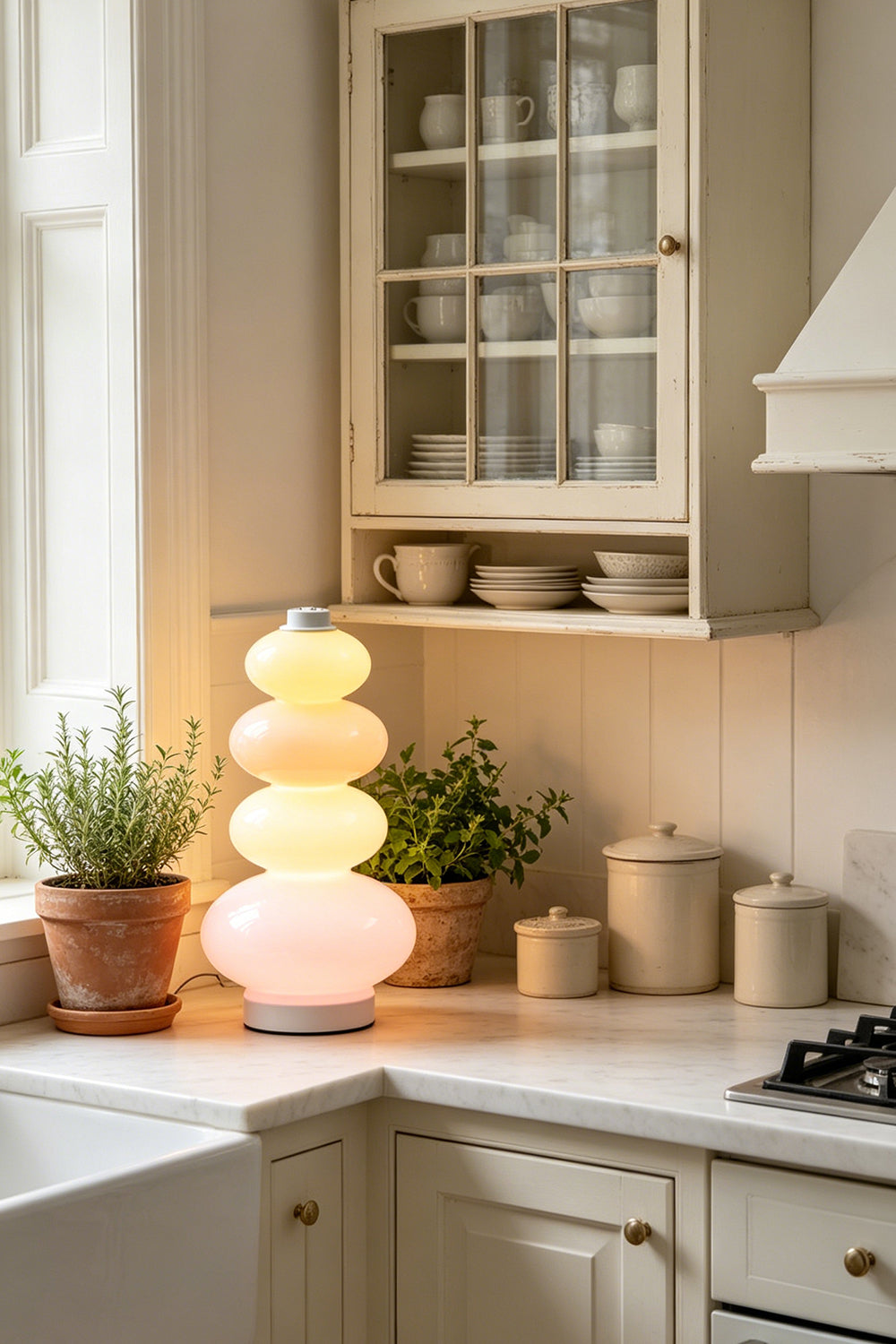 Dolce Stacked Pastel Glass Table Lamp | Glass, Metal | Placed on a classic white kitchen counter next to terracotta herb pots and traditional cabinetry | vexa lamps