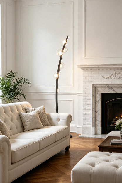 Drosia Dewdrop Floor Lamp | Glass, Metal | Casting a welcoming glow in a sophisticated living space corner next to a cream fabric sofa and a classic fireplace mantle | vexa lamps