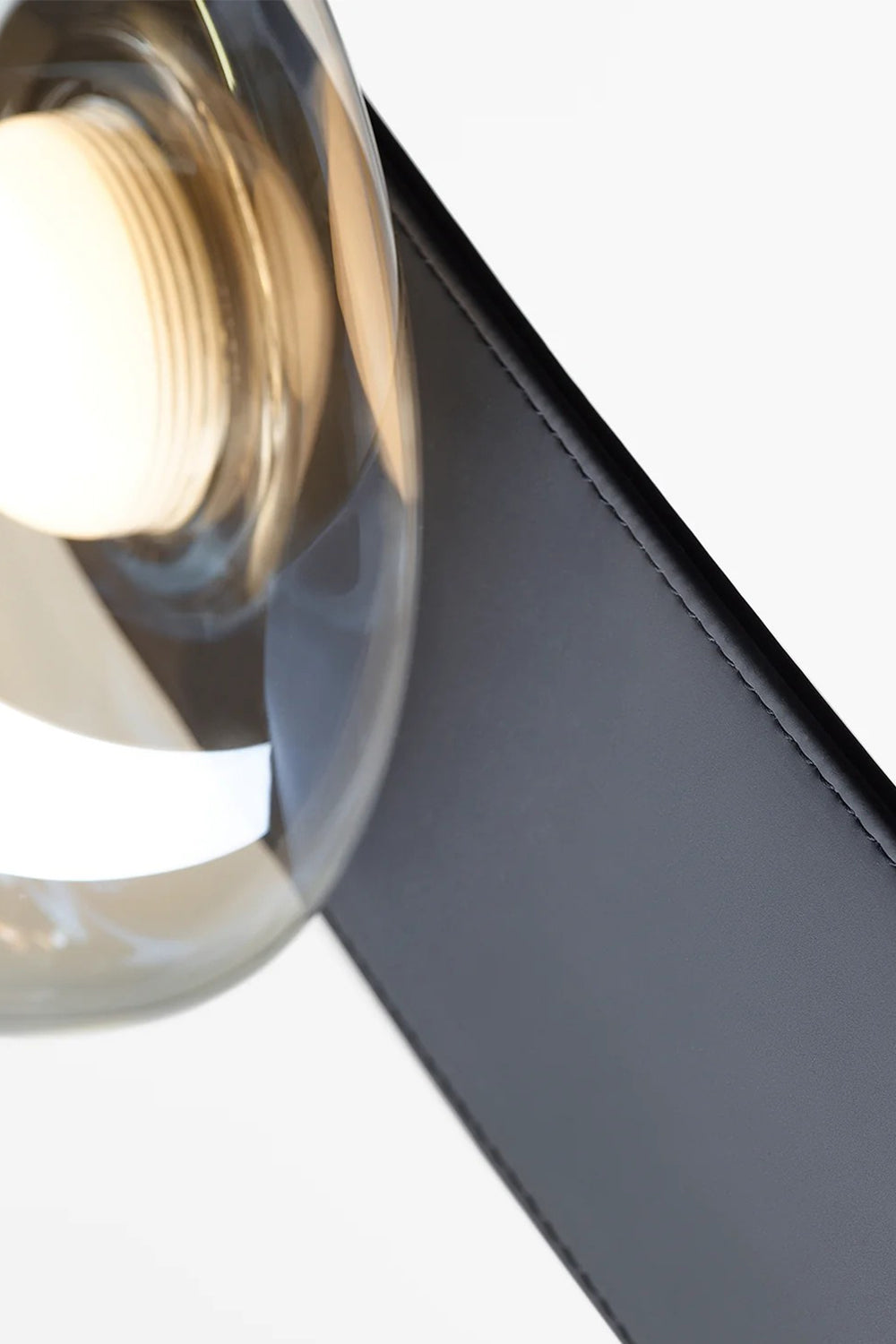 Drosia Dewdrop Floor Lamp | Glass, Metal | Macro close-up structural view showing a single transparent glass sphere seamlessly meeting the curved edge of the matte black metallic stem | Detail shot | vexa lamps