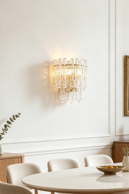 Elara Textured Cast Glass Wall Lamp | Textured Cast Glass, Polished Brass | Close-up view of the illuminated lamp installed on a wall, highlighting the intricate pattern and warm, diffused light filtered through the artisanal glass panels | vexa lamps