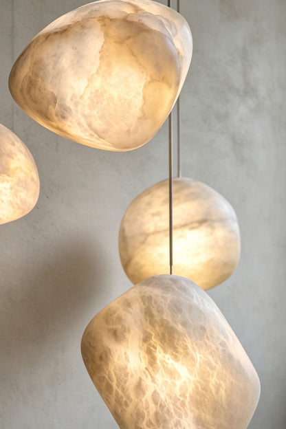 Elodie Teardrop Alabaster Pendant Light showcasing its unique, hand-chiseled organic shape and illuminating glow.