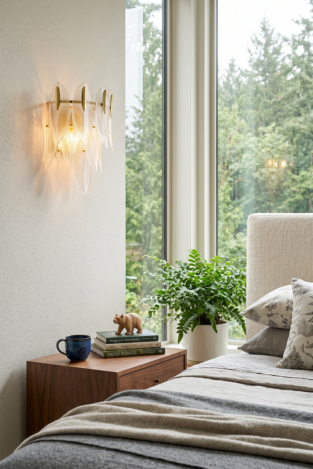 Elowen Cascading Glass Wall Lamp | Glass, Metal | Mounted as a cozy bedtime reading light on a white wall next to a plush bed and a sunlit window with a forest view | vexa lamps