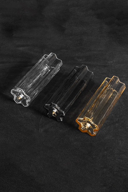 Elysian Tiered Fluted Ceiling Light | Glass, Metal | Close-up focus on three variant options of fluted glass prism rods (clear, smoky, and amber) resting on a black background | Detail shot | vexa lamps