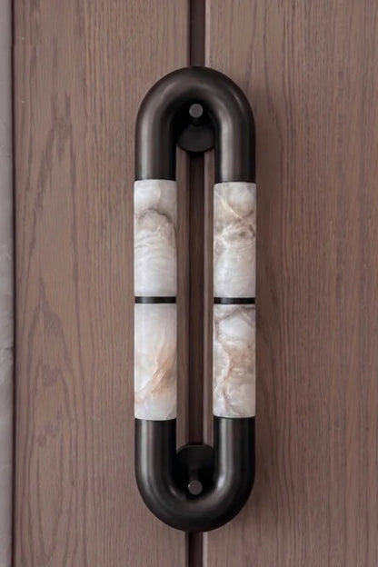Evadne Alabaster Link Wall Sconce | Alabaster, Metal | Sconce unlit or in dim lighting mounted vertically on a dark wood-paneled wall, showing its architectural pill-shaped outline | vexa lamps