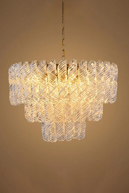 Evangeline Tiered Twisted Glass Chandelier | Studio Lit Presentation | Fully lit tiered luxury glass chandelier casting a deep warm golden halo against a neutral beige background | vexa lamps