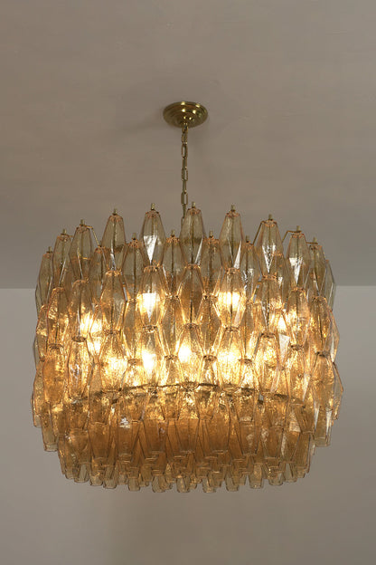 Lit faceted amber glass chandelier | Metal, Glass | Side view against a dark background showing warm glow | vexa lamps