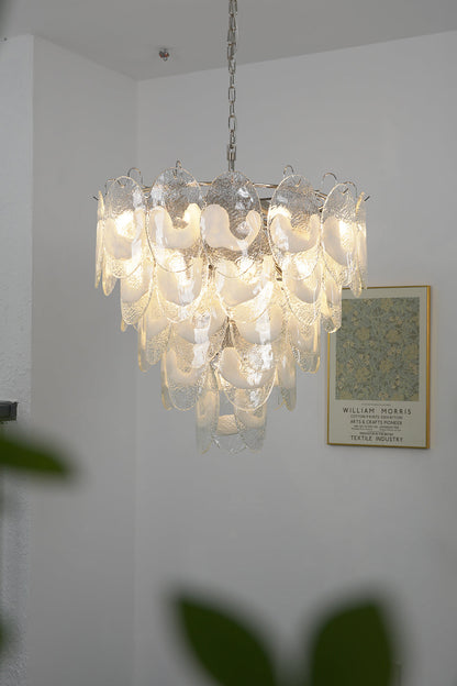 Lit Frostelle Art Chandelier against a white wall | Metal, Glass | Close-up view showing the warm glowing leaves | vexa lamps