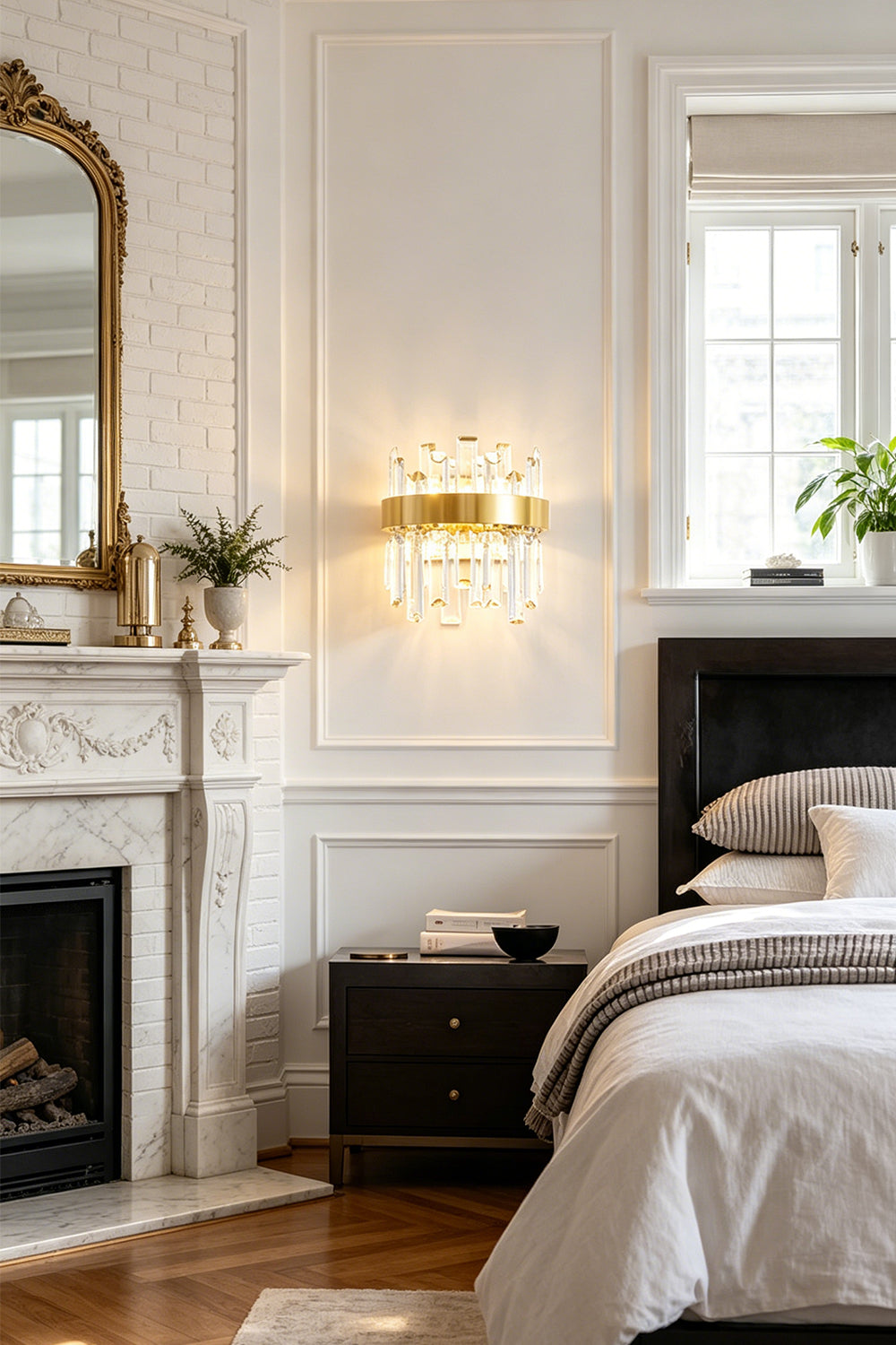 Glacia Tiered Crystal Statement Wall Lamp | Crystal, Metal | Installed on a white wall over a dark wood nightstand next to a classical fireplace mantle with a gold mirror in a refined bedroom suite | vexa lamps