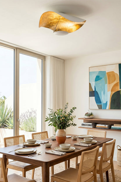 Gold-Tone Sculptural Ceiling Light illuminating a dining area with modern decor and plants.