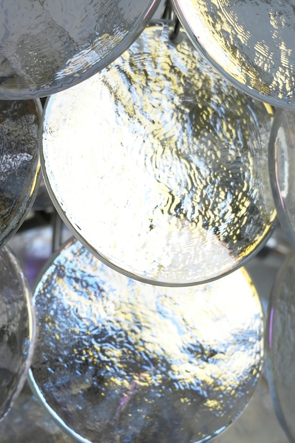Lit iridescent glass discs detail | Glass | Close-up of glowing glass panels and hooks | vexa lamps