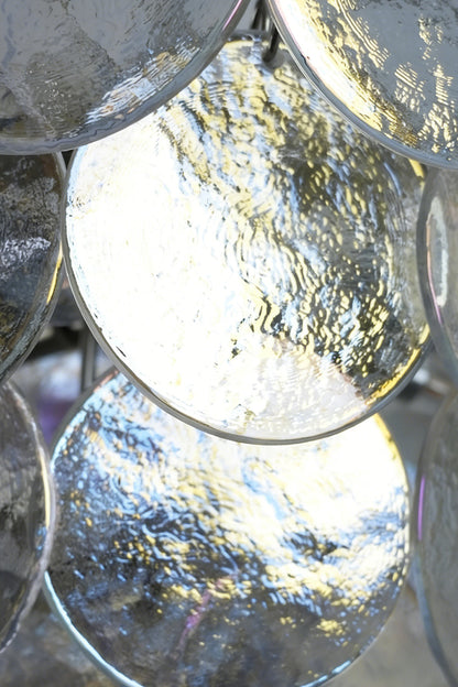 Lit iridescent glass discs detail | Glass | Close-up of glowing glass panels and hooks | vexa lamps