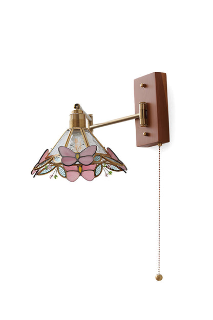 Iris Butterfly Stained Glass Wall Lamp | Stained Glass, Metal, Wood | Fully lit conical Tiffany-style stained glass wall sconce featuring pink butterflies, an adjustable gold brass swing arm, and a rectangular wood backplate with a pull chain | Isolated product shot on white background | vexa lamps