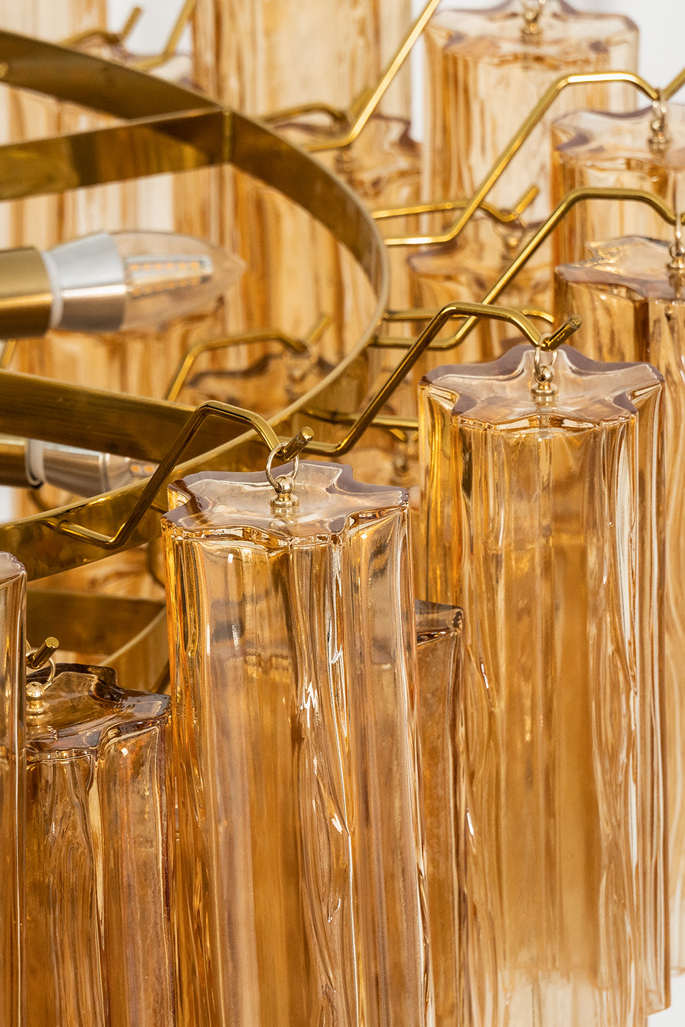 Close-up of amber glass chandelier highlights its elegant glass prisms and metallic details.