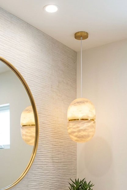 Isaline Banded Capsule Alabaster Pendant Light illuminating a modern interior, featuring sleek design and soft hues.