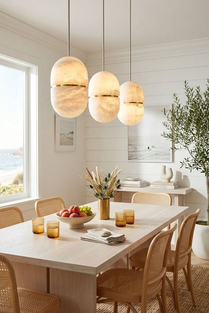 Isaline Banded Capsule Alabaster Pendant Light hanging above a dining table in a bright, airy dining room.