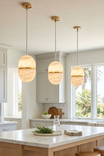 Isaline Banded Capsule Alabaster Pendant Light hanging in a modern kitchen above an island.